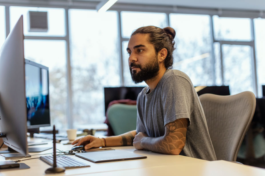 Man sitting at computer looking at two screens